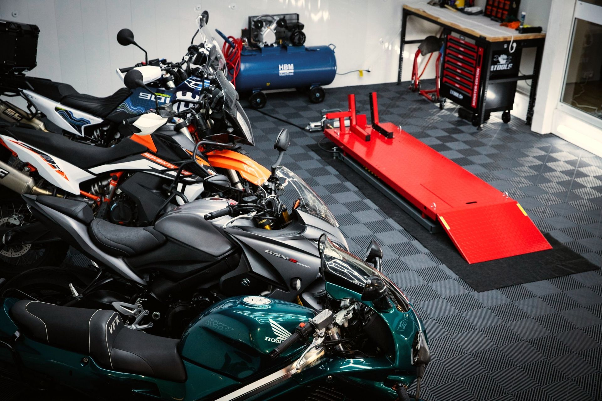 L’espace atelier de DVA MOTO : pont élévateur, compresseur et servante, motos prêtes à être préparées